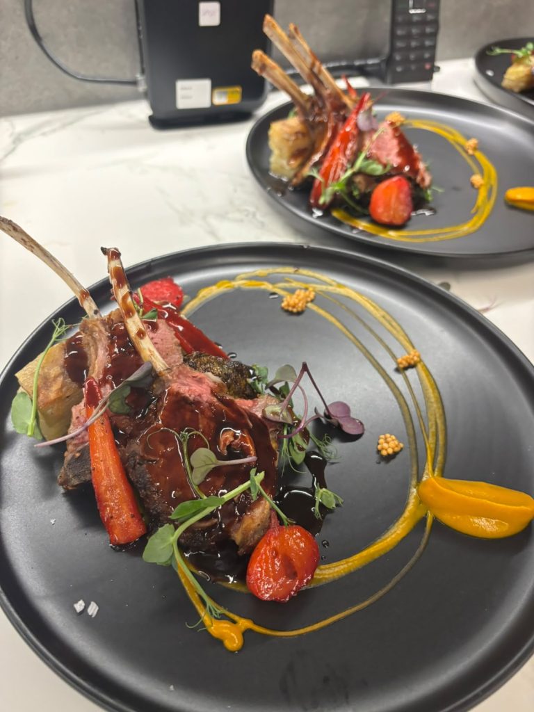 Herb-crusted lamb rack with roasted heritage carrots and blistered tomato