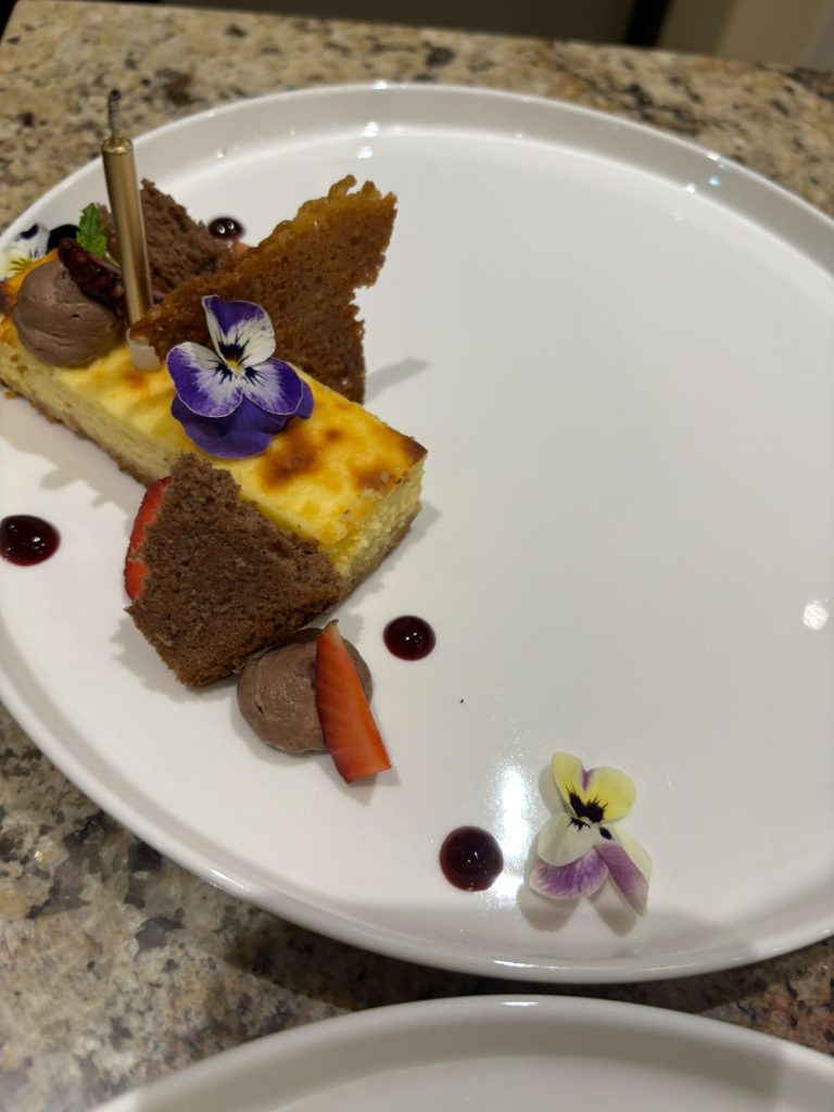 Baked cheesecake with a chocolate mousse quenelle and edible flowers