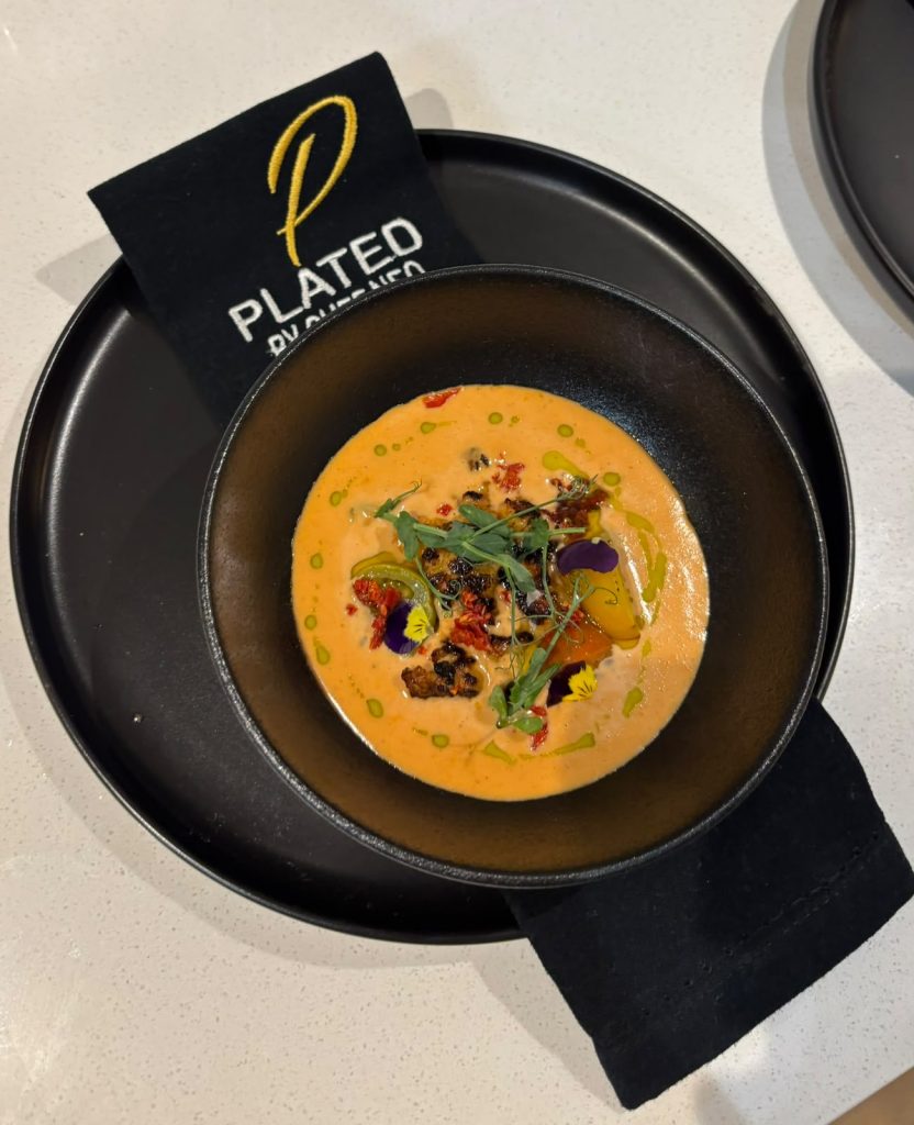 Shellfish bisque with micro herbs on branded service linen